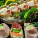 Delicious open-faced sandwiches with ham, eggs, and veggies on a wooden platter.